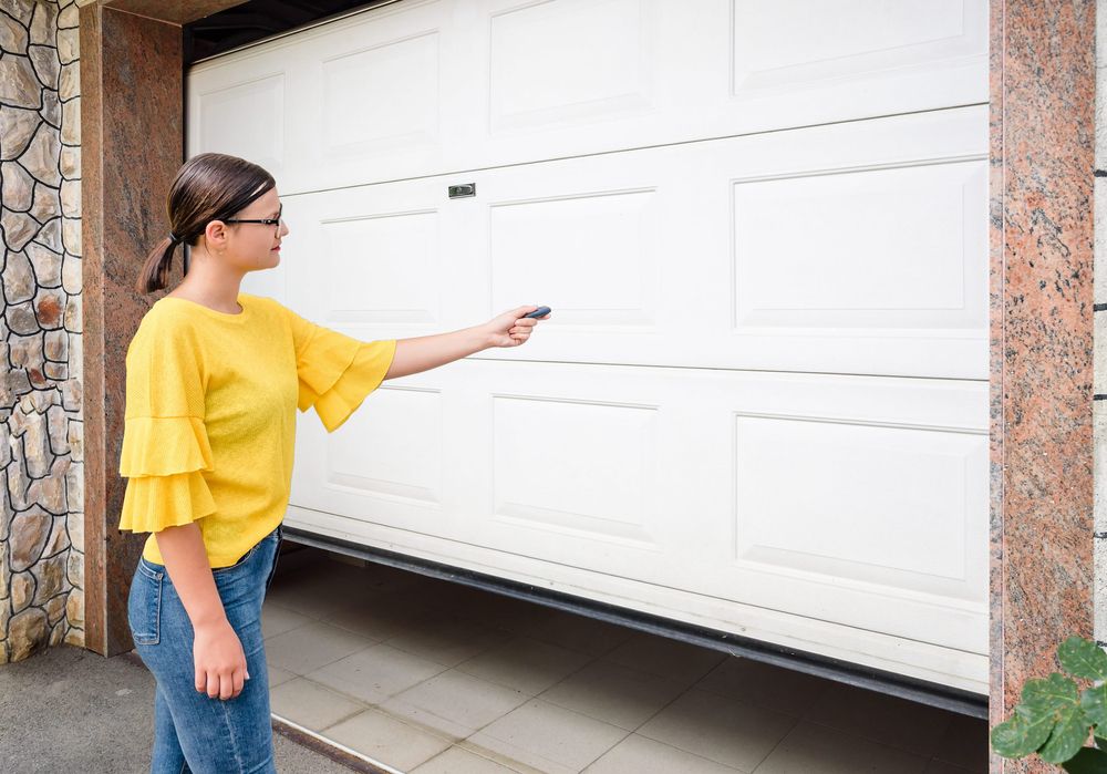 Young Woman Using Remote To Open The Garage — Garage Doors in Casuarina, NSW